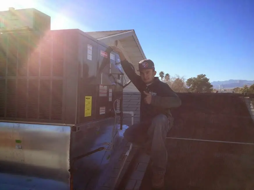 HVAC technician performing AC Tune-Up on a rooftop unit in Essex Junction